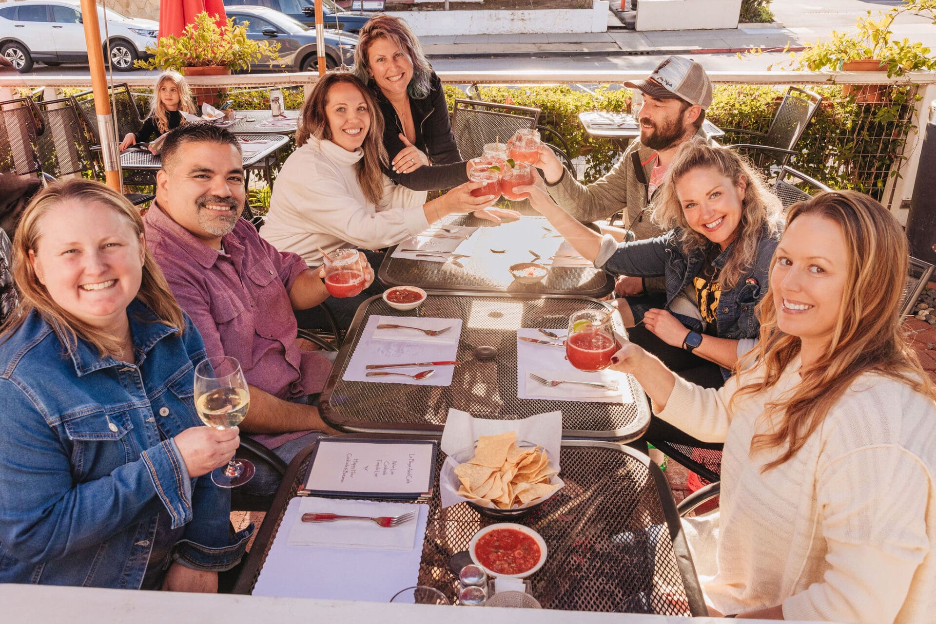 Group of people during the Taco Tour in Santa Barbara hosted by Taste Santa Barbara Food Tours holding wine glasses and margaritas and posing for the picture.